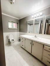 Bathroom featuring a textured ceiling, vanity, crown molding, tile walls, and toilet