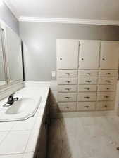 Bathroom featuring tile patterned flooring, vanity, and ornamental molding