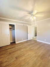 Unfurnished bedroom with ceiling fan, crown molding, hardwood / wood-style floors, a textured ceiling, and a closet