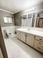 Bathroom with walk in shower, vanity, crown molding, tile walls, and toilet