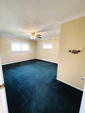 Empty room with a baseboard heating unit, carpet floors, ceiling fan, and ornamental molding