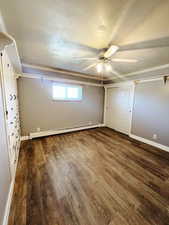 Unfurnished bedroom featuring ceiling fan, dark wood-type flooring, a baseboard radiator, and a textured ceiling