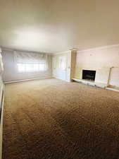 Unfurnished living room featuring carpet, ornamental molding, and a baseboard heating unit