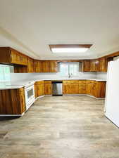 Kitchen with light hardwood / wood-style floors, white appliances, and sink