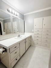 Bathroom with tile patterned flooring, vanity, crown molding, and a textured ceiling