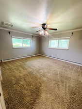 Carpeted spare room with a baseboard radiator, plenty of natural light, crown molding, and ceiling fan