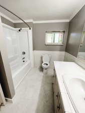 Full bathroom with crown molding, toilet, shower / bathtub combination, vanity, and tile walls