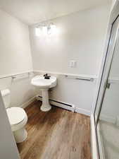 Bathroom with hardwood / wood-style flooring, toilet, and a baseboard heating unit