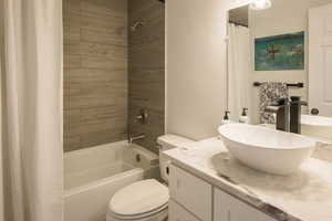 Primary Full bathroom featuring shower / bath combo, toilet, and quartz vanity with designer sink