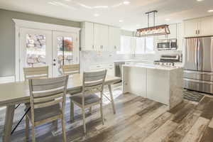 Kitchen with white cabinetry, stainless steel appliances, pendant lighting, light, and LVP floors