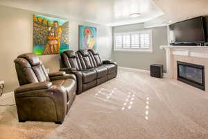 Family room featuring a tiled fireplace and light colored carpet Daylight window with plantation shutters