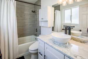 Full main bathroom featuring vanity, cabinet over toilet, and shower / bathtub combination with large vanity