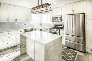 Kitchen featuring white cabinetry, a center island, corner sink & window with great views