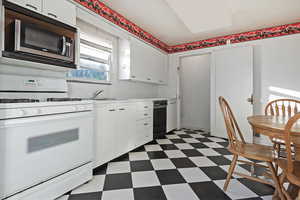 Kitchen with white cabinetry, sink, and white range with gas cooktop