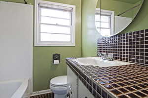 Full bathroom featuring backsplash, shower / bathtub combination, sink, tile patterned flooring, and toilet