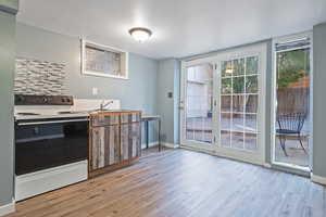 Kitchen featuring electric stove, sink, and light wood-type flooring