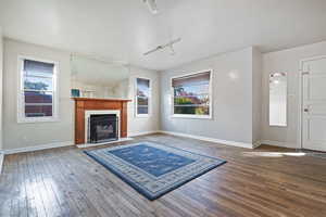 Unfurnished living room featuring a fireplace, rail lighting, and hardwood / wood-style flooring