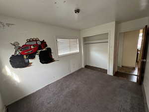 Bedroom with dark colored carpet and a closet