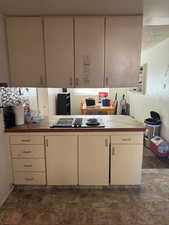 Kitchen featuring kitchen peninsula, tile countertops, cream cabinets, and stainless steel gas cooktop