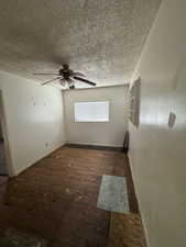 Unfurnished room featuring ceiling fan, a textured ceiling, and dark wood-type flooring