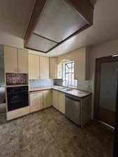 Kitchen featuring dishwasher, tasteful backsplash, black oven, and sink