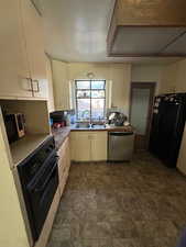 Kitchen with cream cabinets, sink, and black appliances