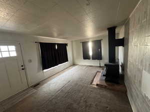 Unfurnished living room featuring a wood stove and carpet floors