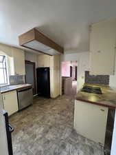 Kitchen featuring cream cabinets, backsplash, and black appliances