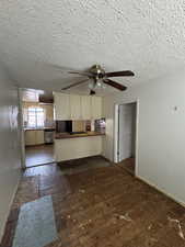 Unfurnished living room featuring a textured ceiling, ceiling fan, sink, and dark hardwood / wood-style floors