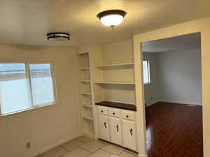 Interior space with built in shelves, a textured ceiling, and light hardwood / wood-style flooring