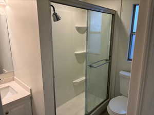 Bathroom with vanity, toilet, and an enclosed shower