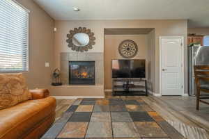 Living room featuring a textured ceiling, a tiled fireplace, and dark hardwood / wood-style floors