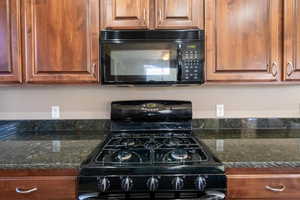 Kitchen featuring black appliances and dark stone counters