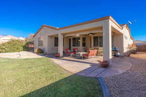 Rear view of property featuring ceiling fan, a yard, and a patio