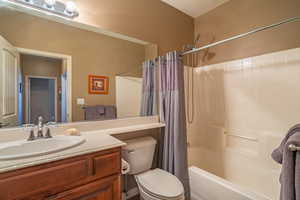 Full bathroom featuring vanity, shower / bath combination with curtain, a textured ceiling, and toilet