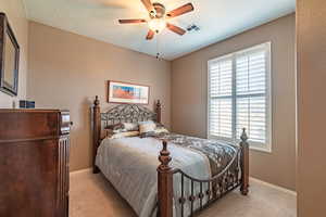 Carpeted bedroom featuring ceiling fan and a textured ceiling