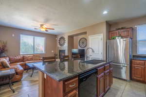 Kitchen featuring a kitchen island with sink, sink, light hardwood / wood-style flooring, dishwasher, and stainless steel refrigerator