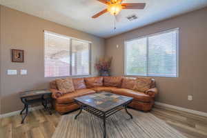 Living room featuring ceiling fan, light wood-type flooring, and a textured ceiling