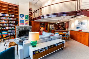 Carpeted living room with a stone fireplace and track lighting