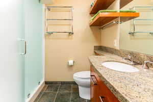 Bathroom with tile patterned floors, vanity, toilet, and a shower with door