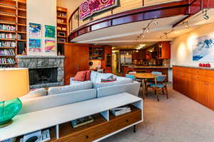 Carpeted living room with built in features and a stone fireplace