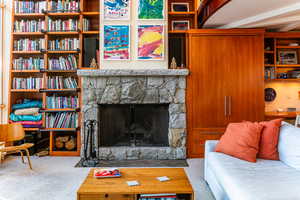 Carpeted living room featuring beam ceiling and a fireplace