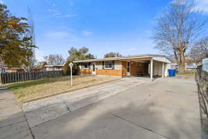 Single story home featuring a front lawn and a carport