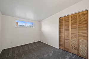 Unfurnished bedroom featuring dark carpet and a closet