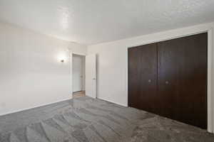 Unfurnished bedroom with light carpet, a closet, and a textured ceiling