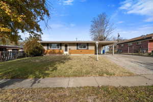 Single story home with a front lawn and a carport