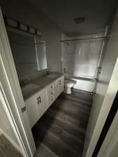 Full bathroom with shower / tub combination, vanity, wood-type flooring, and toilet