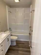 Full bathroom with hardwood / wood-style flooring, vanity,  shower combination, and toilet