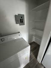 Clothes washing area with electric panel, dark hardwood / wood-style flooring, and washer / dryer