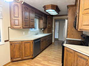 Kitchen with sink, black appliances, a textured ceiling, and light wood-type flooring